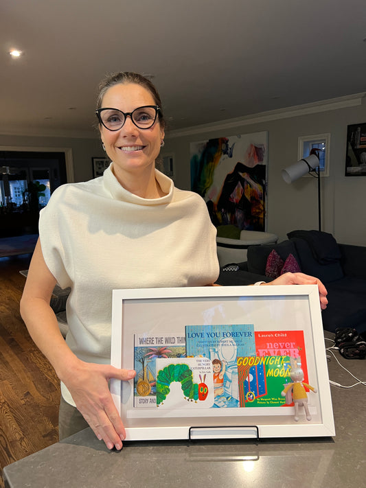 jennifer steckel elliott shows a Lagom Collections wall art Kids Shelf Portrait featuring Goodnight Moon, Hungry Caterpiller, Love you Forever, Where the Wild Things Are, and Charlie & Lola